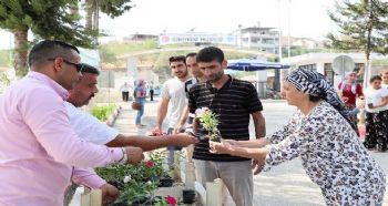 MEZARLIK KAPISINDA VATANDAŞA ÇİÇEK VE SU